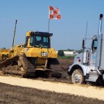 Dozer pulls trucks through wet subgrade conditions providing consistent distribution of fly ash per square yard.